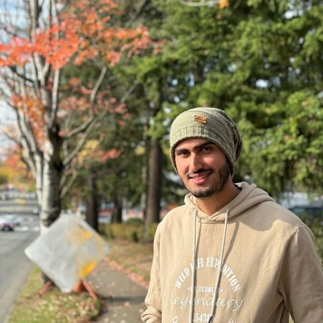 Nima Kelidari, outdoors on a tree-lined street in autumn